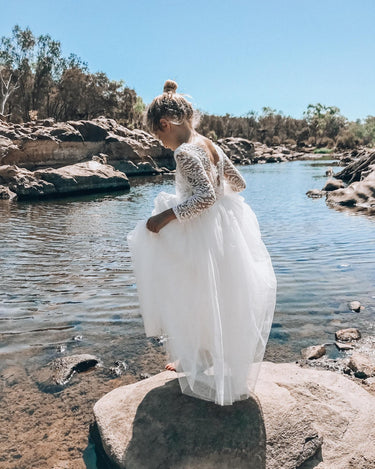 Model standing on a rock in the Swan White Lace Back Dress