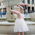 Willow standing in front of a fountain in the White Rosetta Lace Dress