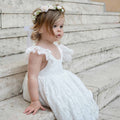 Willow sitting on the stairs in the White Rosetta Lace Dress