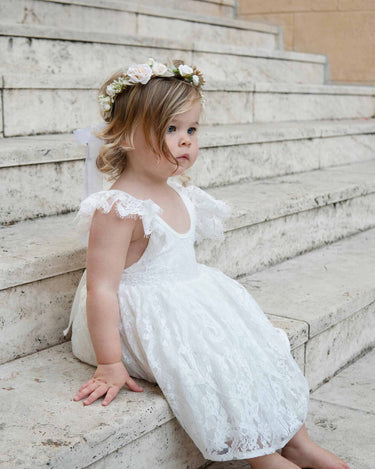 Willow sitting on the stairs in the White Rosetta Lace Dress